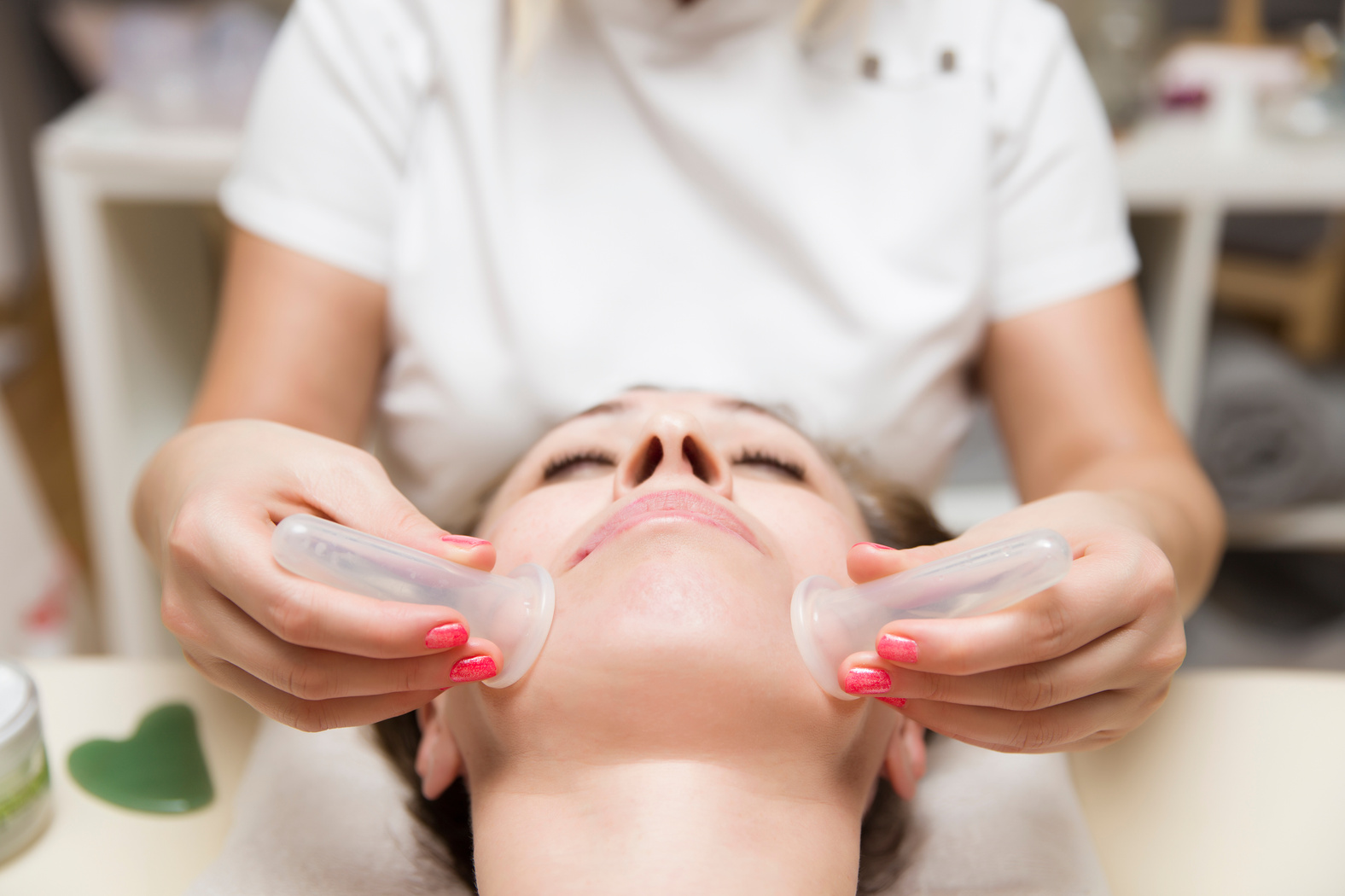 Cup applied to facial skin of a female patient as part of the traditional method of cupping therapy